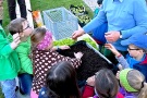 Kinder befüllen eine Pflanzkiste mit Erde.