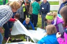 Kinder decken Beete mit einem Fließ zum Schutz vor Kälte zu. 
