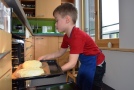 Kind schiebt Brot in den Ofen