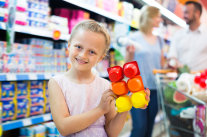 Kind hält sechsteilige Joghurtverpackung in Supermarkt