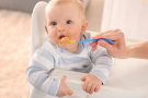 Baby isst Brei von einem Plastiklöffel