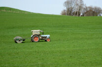 Traktor mit Walze auf Grünland 